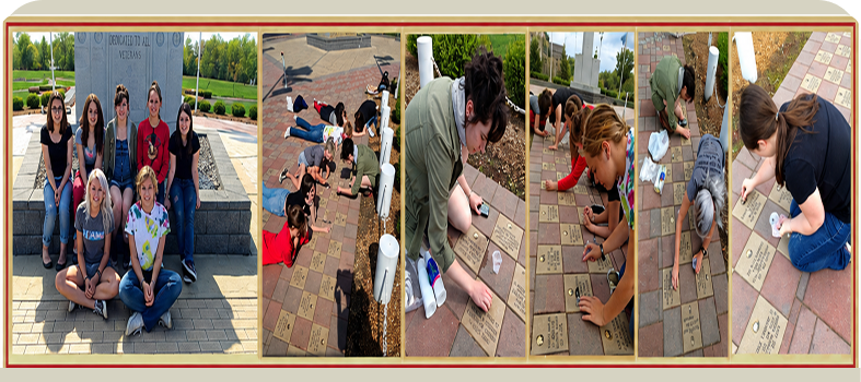 Group cleaning bricks at outdoor memorial site.