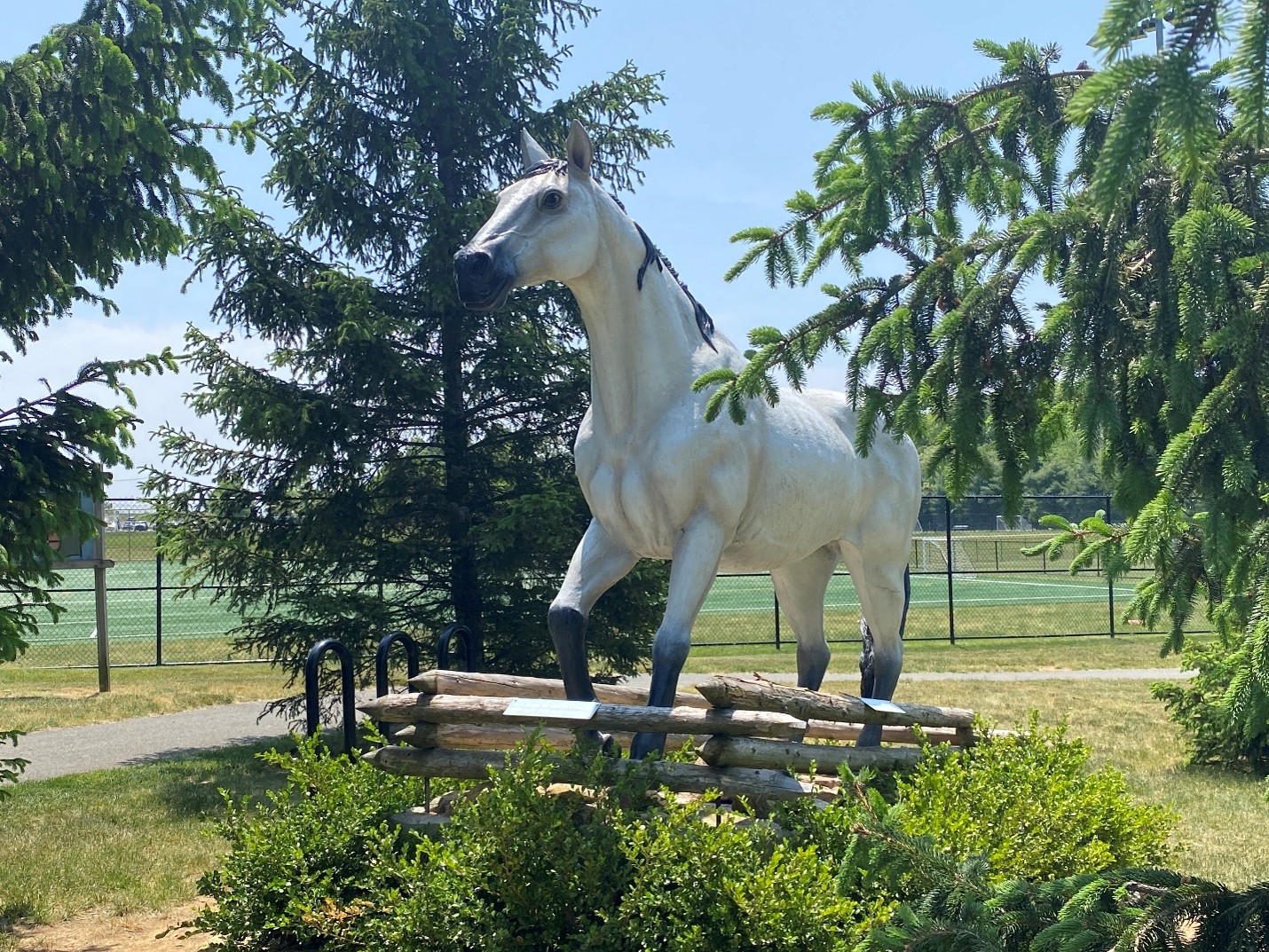 White horse statue among green trees