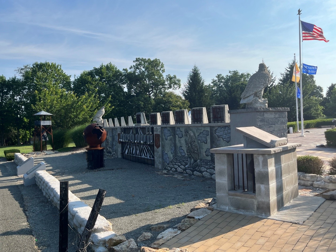 Memorial site with flags and stone sculptures.