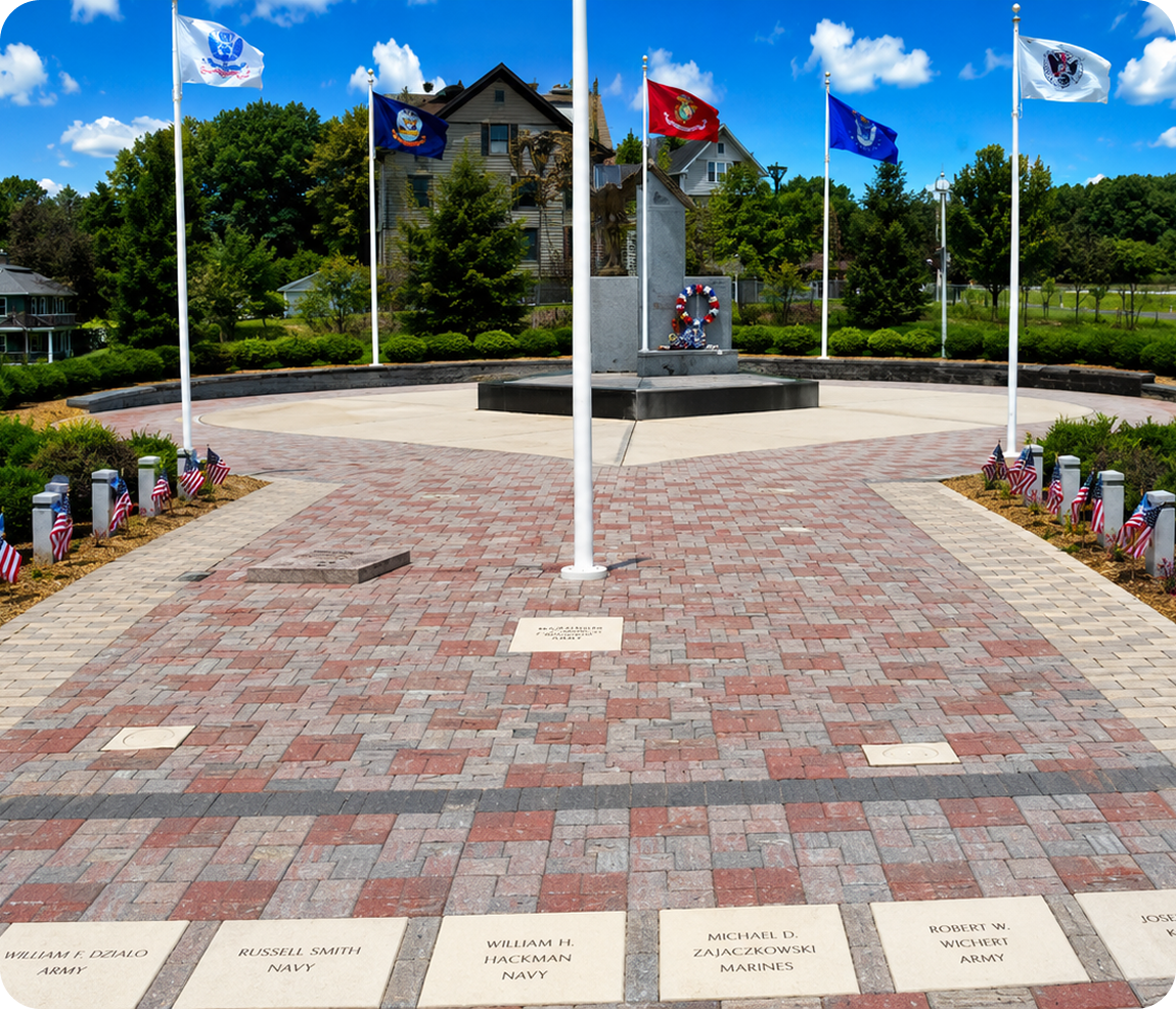 Military memorial with flags and engraved bricks.