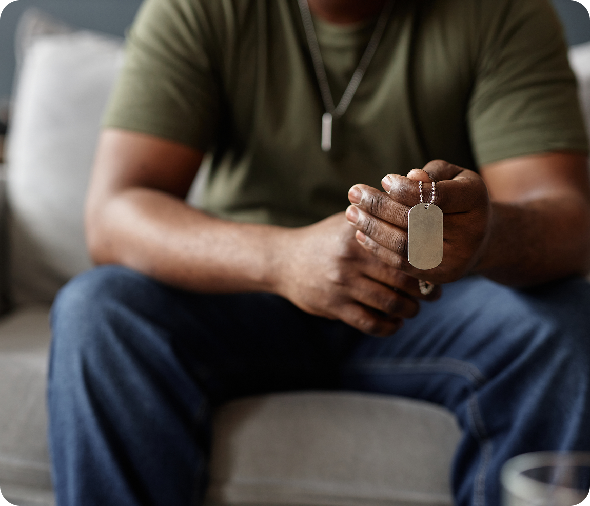 Man holding military dog tags on couch.