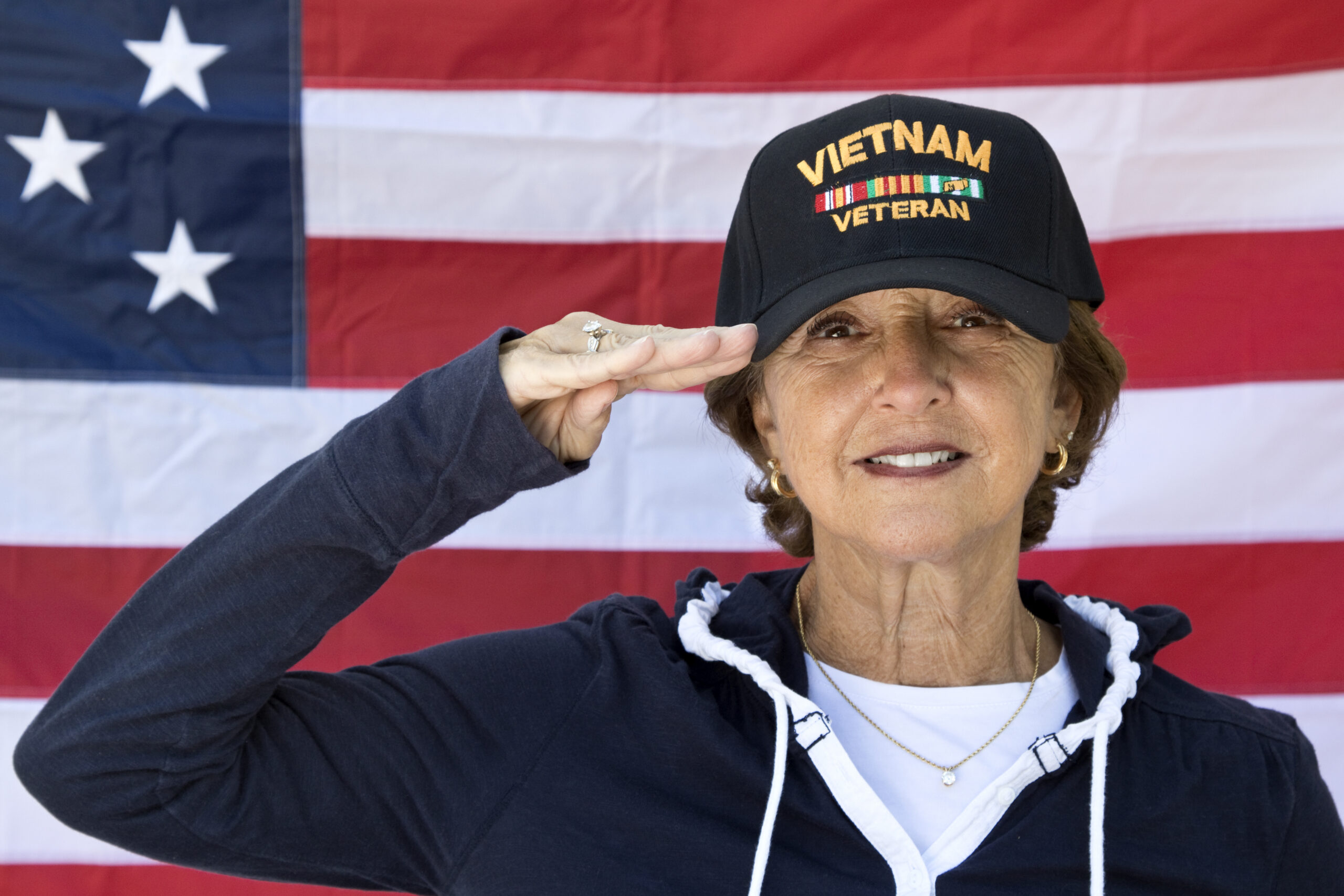 Woman saluting in front of American flag.